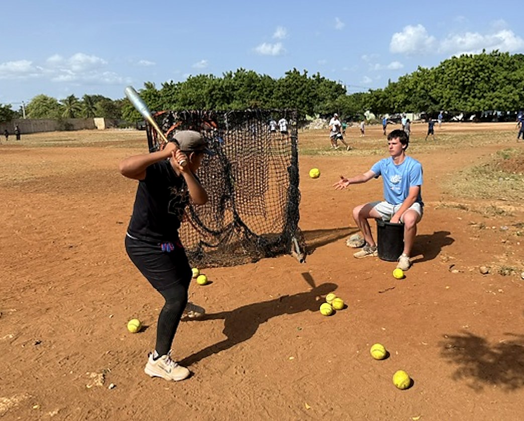 A young batter taking swings on a dirt field in the Dominican Republic