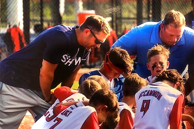 Coaches and players praying together on the field before a game
